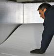 A contractor installing TerraBlock™ floor insulation in a Oak View crawl space