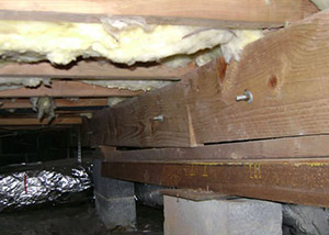 A sagging crawl space with concrete supports and wooden shimming a Simi Valley crawl space