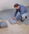 Contractors installing basement subfloor tiles and matting on a concrete basement floor in Summerland, California